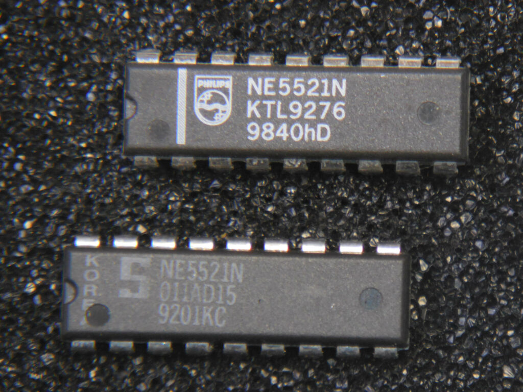 Two 18-pin integrated circuits labeled NE5521N with a background of antistatic foam. The topmost chip bears the Philips logo and a date code of 40th week of 1998. The bottom chip has a Signetics logo and a date code of the first week of 1992 from Korea.