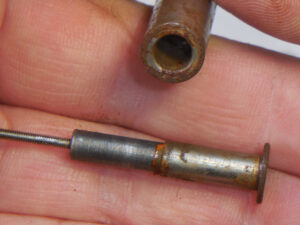 close up image of a hand holding a rusty core holder and rusty plunger from a CAT head